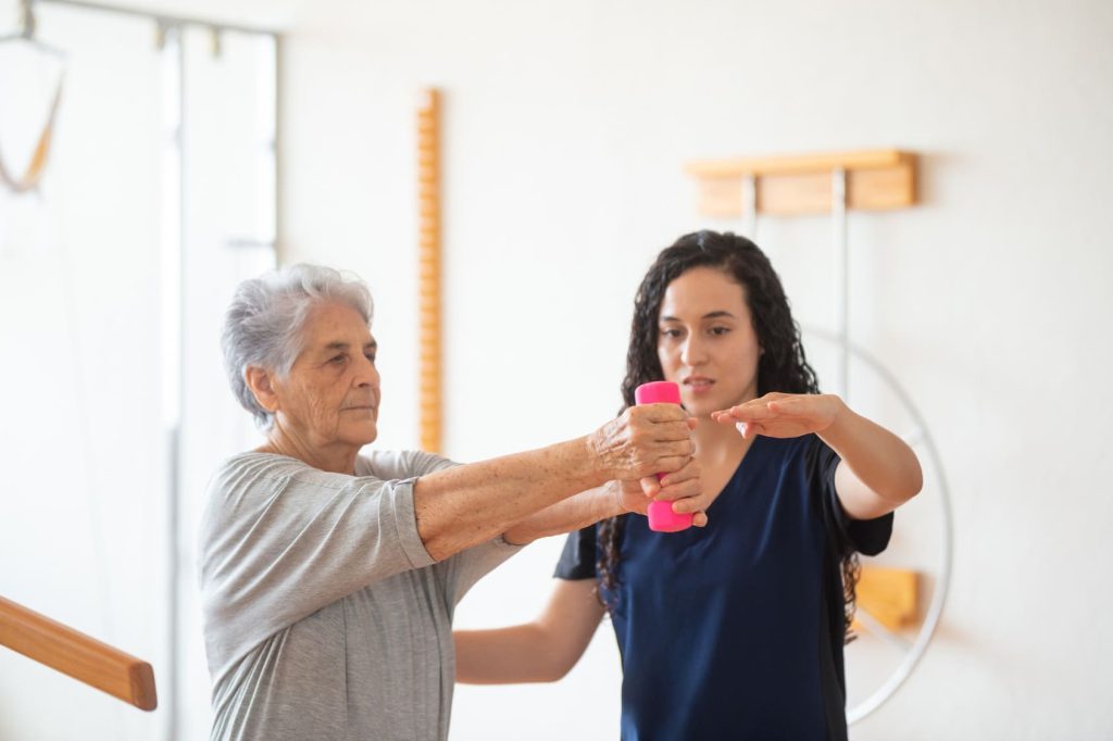 Grand-mother-exercise-dumble-assisted-by-nurse